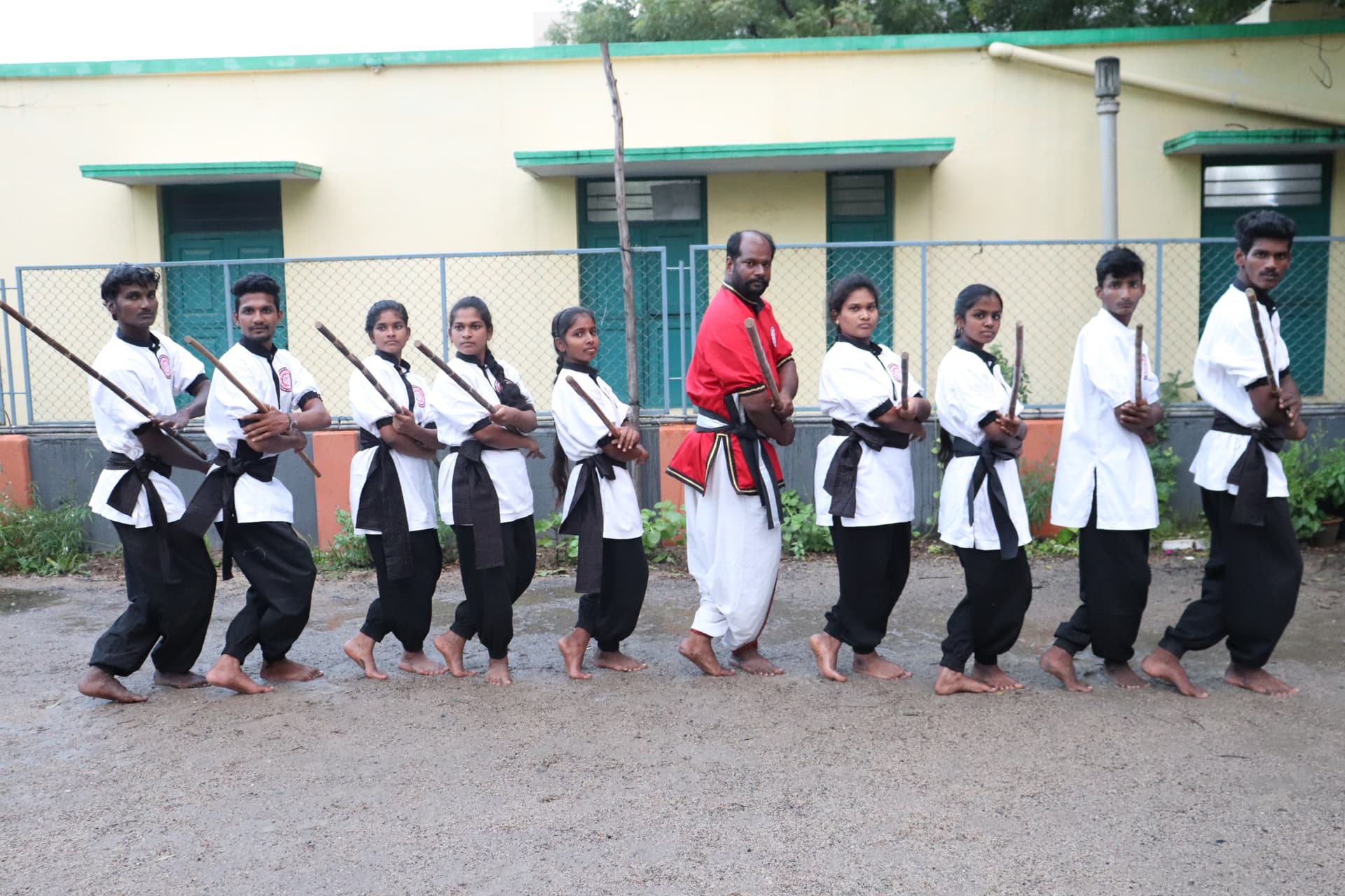 Tamil martial arts instructor teaching silambam staff fighting formation to students in traditional training ground