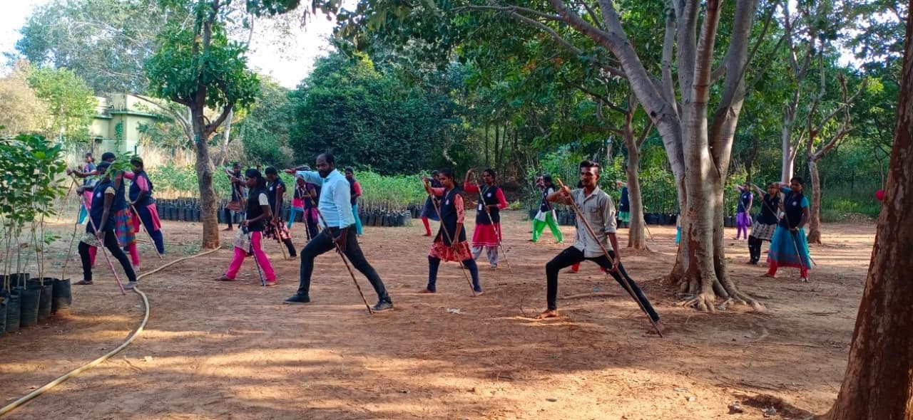 Tamil martial arts students performing synchronized outdoor silambam demonstration with traditional weapons