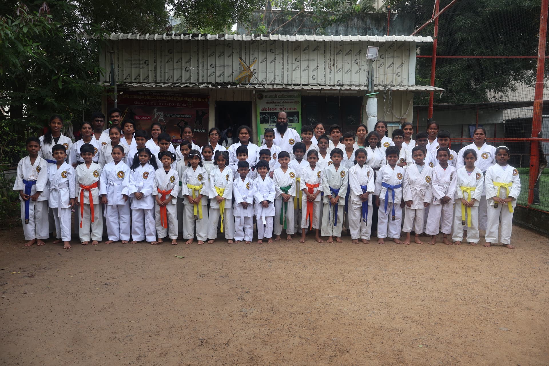 Large group of martial arts students holding certificates after successful belt grading examination ceremony