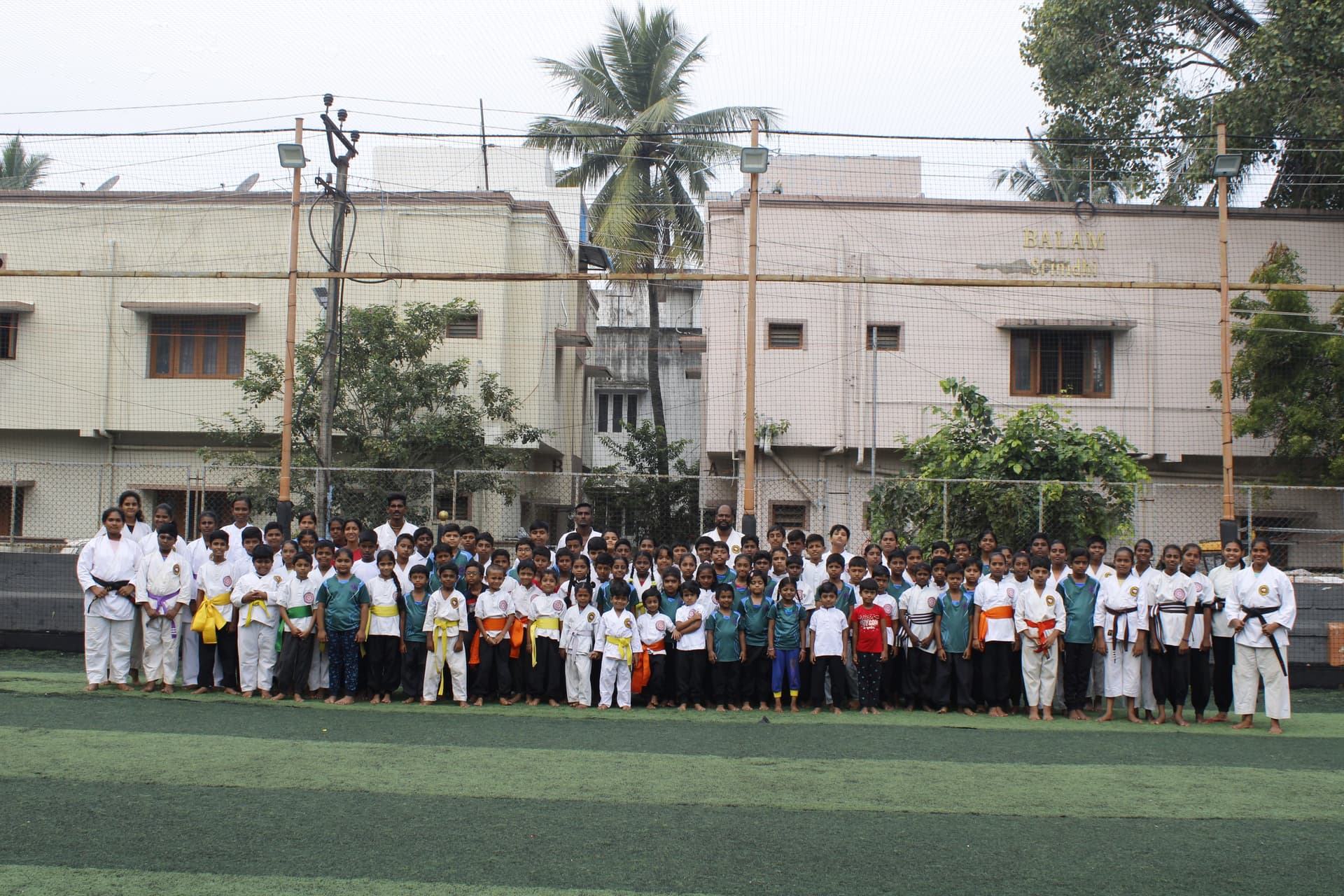 Silambam students holding wooden staffs in synchronized formation during training